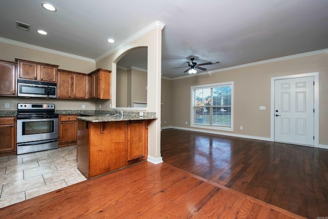 kitchen featuring kitchen peninsula, a kitchen breakfast bar, stainless steel appliances, crown molding, and hardwood / wood-style flooring