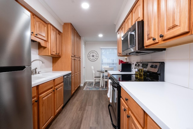 kitchen featuring ornamental molding, stainless steel appliances, dark wood-type flooring, and sink