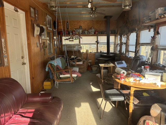 sunroom with a wood stove, ceiling fan, and a healthy amount of sunlight