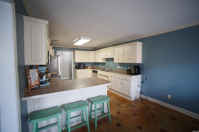 kitchen with kitchen peninsula, ornamental molding, a breakfast bar, sink, and white cabinetry