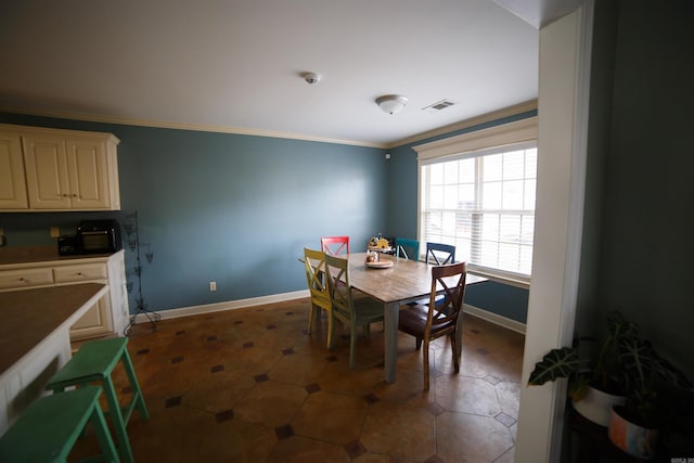 dining area featuring dark tile patterned flooring and ornamental molding