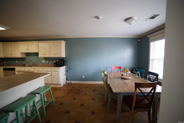 tiled dining room featuring sink and crown molding