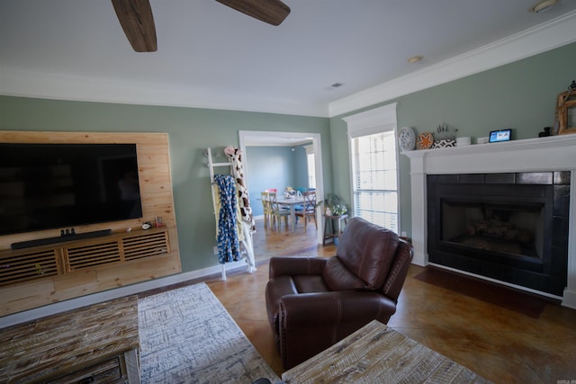 living room with tile patterned flooring, ceiling fan, ornamental molding, and a tiled fireplace