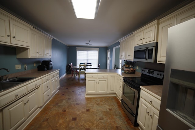 kitchen featuring cream cabinets, crown molding, sink, appliances with stainless steel finishes, and kitchen peninsula