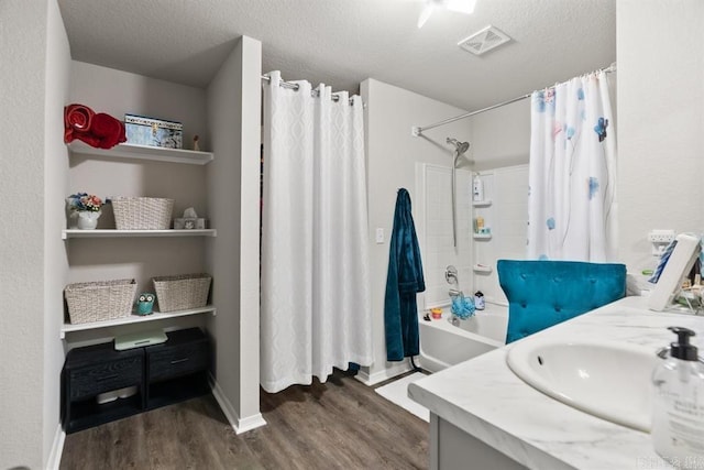 bathroom featuring vanity, hardwood / wood-style floors, a textured ceiling, and shower / bathtub combination with curtain