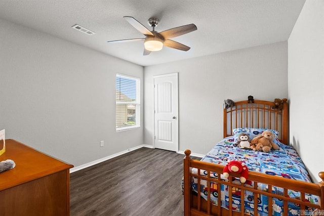 bedroom with a textured ceiling, dark hardwood / wood-style floors, and ceiling fan