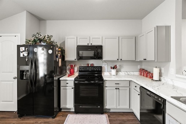 kitchen with light stone counters, dark wood-type flooring, white cabinets, and black appliances