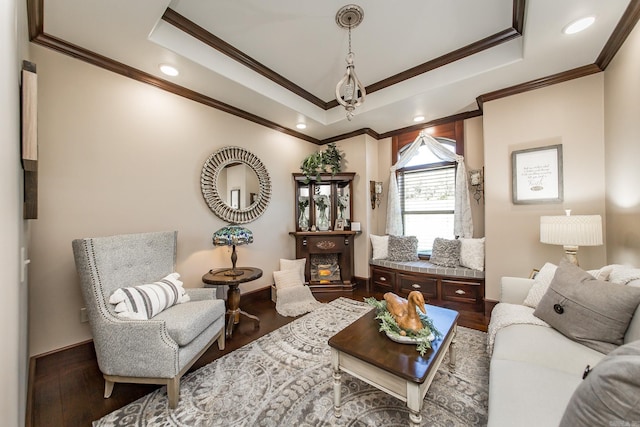 living area with hardwood / wood-style flooring, a raised ceiling, and ornamental molding