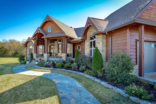 view of front of property featuring a front yard, a garage, and covered porch