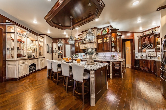 kitchen with crown molding, an island with sink, and decorative light fixtures