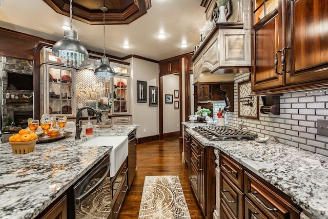 kitchen with light stone counters, dark hardwood / wood-style flooring, pendant lighting, stainless steel gas stovetop, and ornamental molding