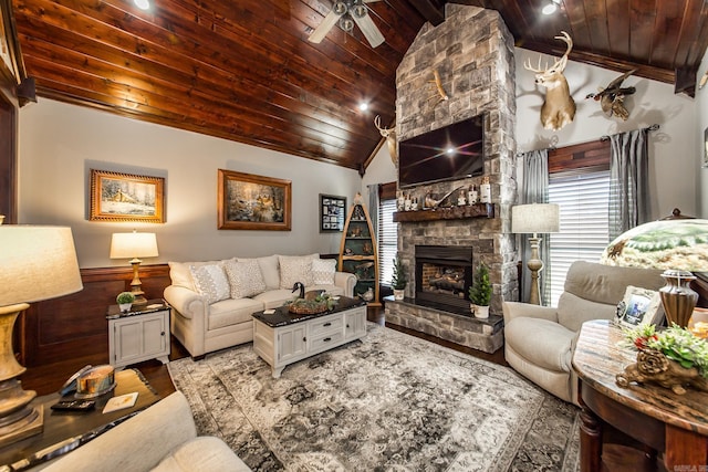 living room with hardwood / wood-style floors, lofted ceiling, a stone fireplace, ceiling fan, and wood ceiling