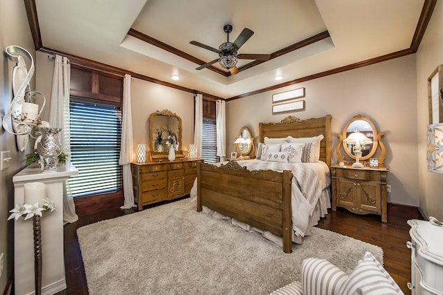 bedroom featuring dark hardwood / wood-style flooring, a tray ceiling, ceiling fan, and ornamental molding