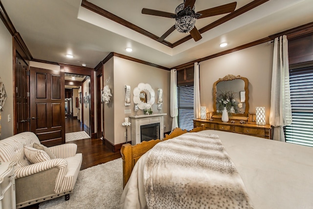 bedroom featuring ceiling fan, dark hardwood / wood-style floors, ornamental molding, and a tray ceiling