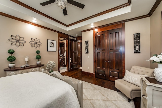 bedroom with a raised ceiling, ceiling fan, crown molding, and dark wood-type flooring