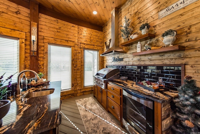 kitchen with sink, beverage cooler, dark stone counters, light hardwood / wood-style floors, and wood ceiling