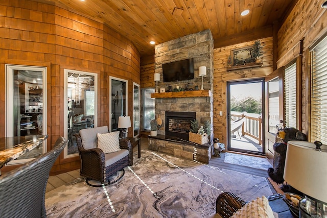 interior space featuring an outdoor stone fireplace, high vaulted ceiling, wooden walls, and wood ceiling