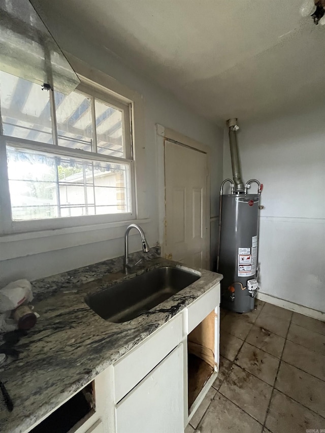 kitchen with white cabinets, sink, light tile patterned floors, water heater, and stone countertops