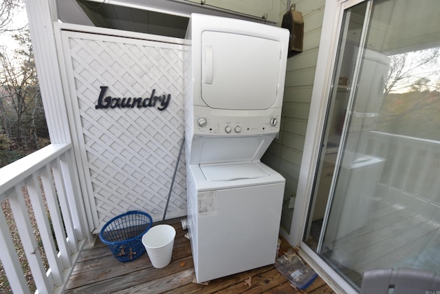 clothes washing area with stacked washer / drying machine and dark hardwood / wood-style floors