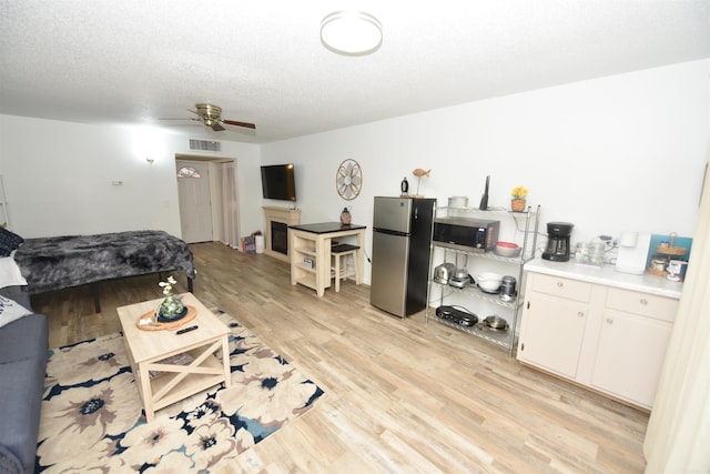 living room featuring a textured ceiling, light hardwood / wood-style floors, and ceiling fan