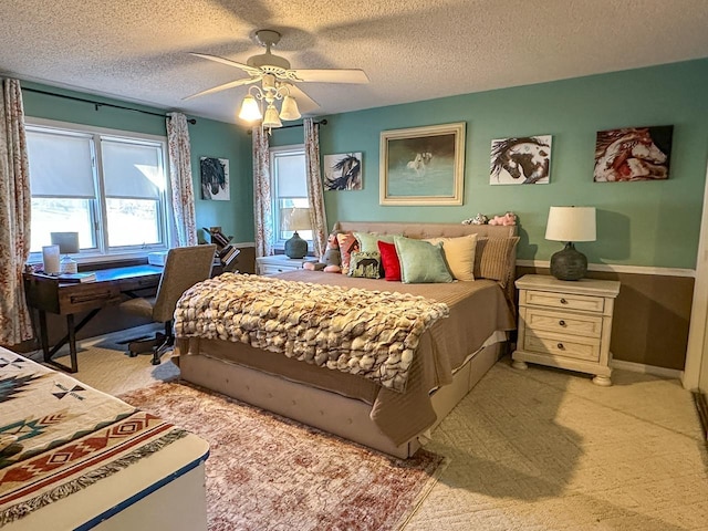 bedroom with ceiling fan, light colored carpet, and a textured ceiling