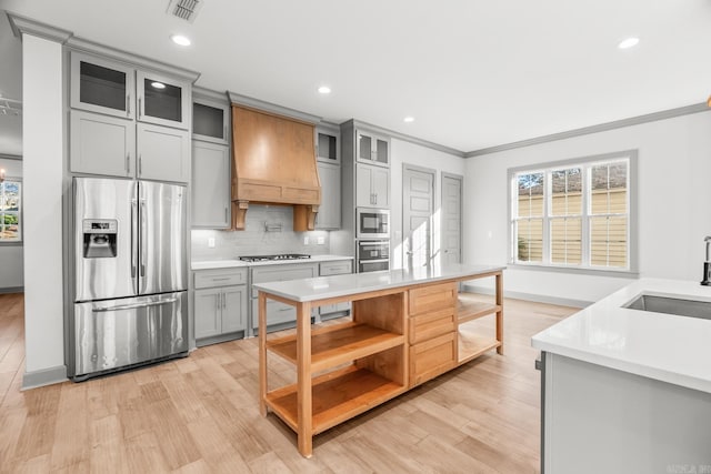 kitchen featuring custom range hood, appliances with stainless steel finishes, gray cabinets, light countertops, and a sink