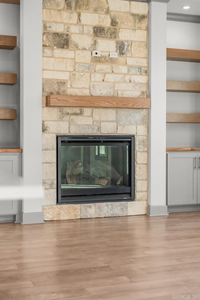 details featuring hardwood / wood-style floors, a stone fireplace, and built in shelves