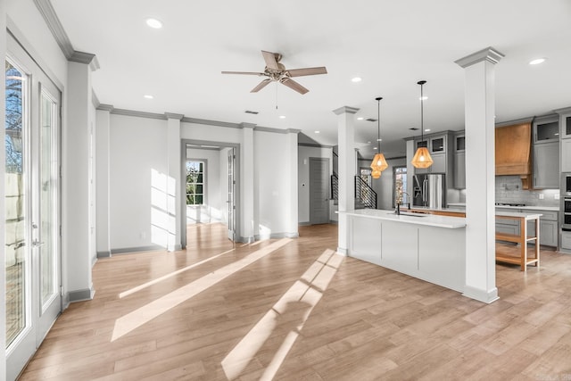 kitchen with light wood-type flooring, tasteful backsplash, ceiling fan, crown molding, and pendant lighting