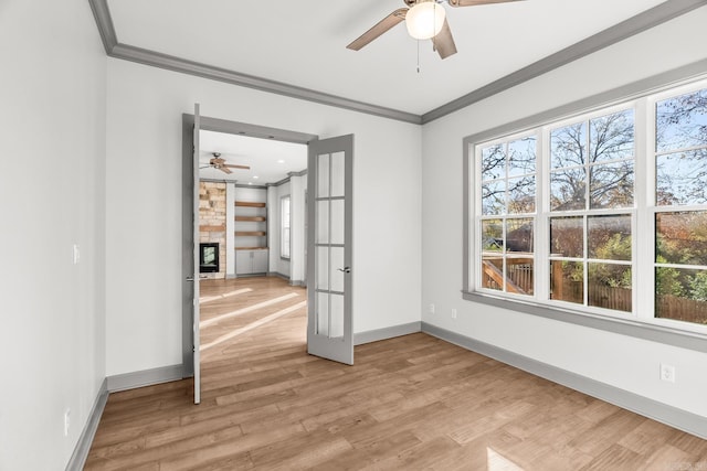 unfurnished room featuring a fireplace, light wood-type flooring, ceiling fan, and crown molding