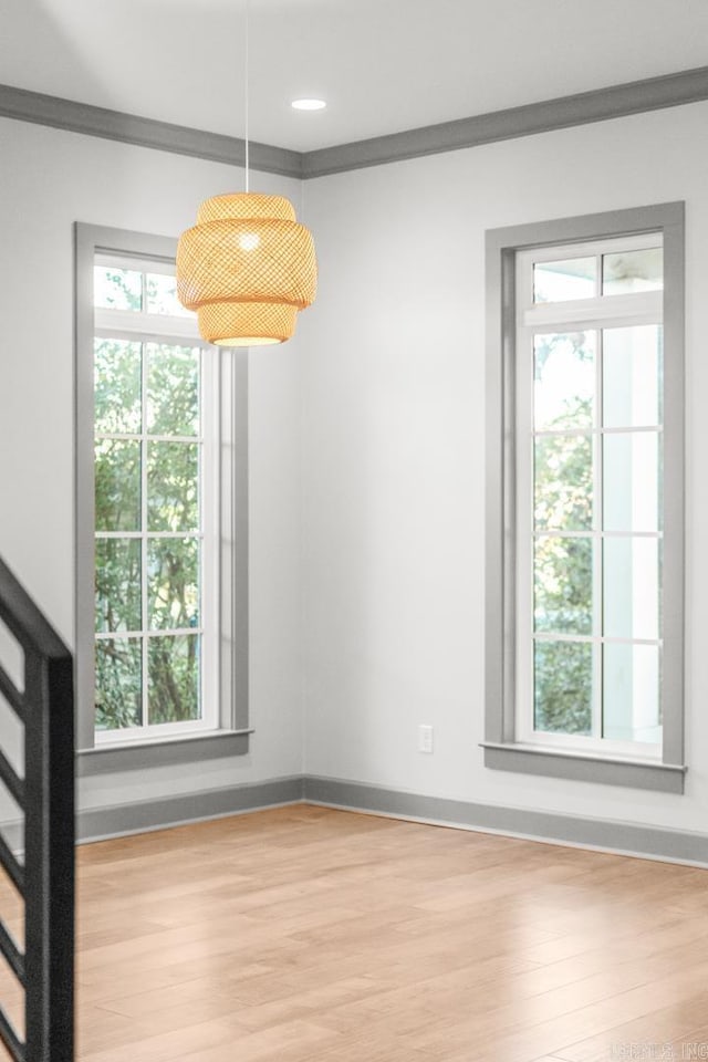 unfurnished dining area featuring crown molding and light hardwood / wood-style flooring