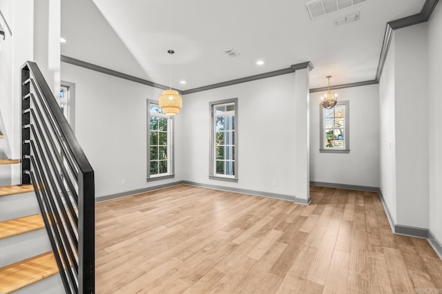 spare room featuring a chandelier, a wealth of natural light, light hardwood / wood-style floors, and ornamental molding