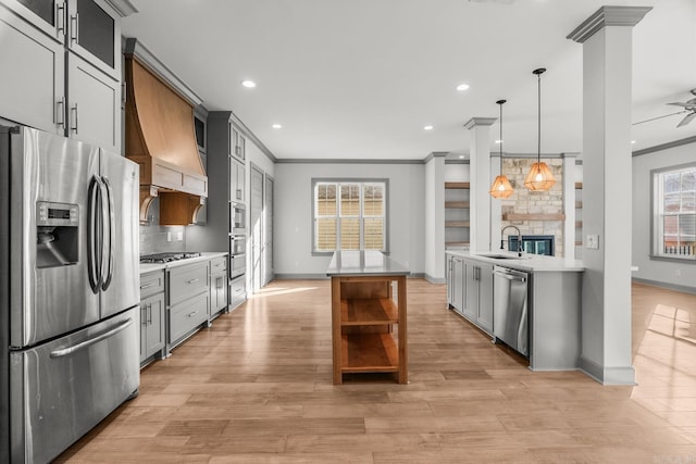 kitchen with a sink, light countertops, ornamental molding, appliances with stainless steel finishes, and open shelves