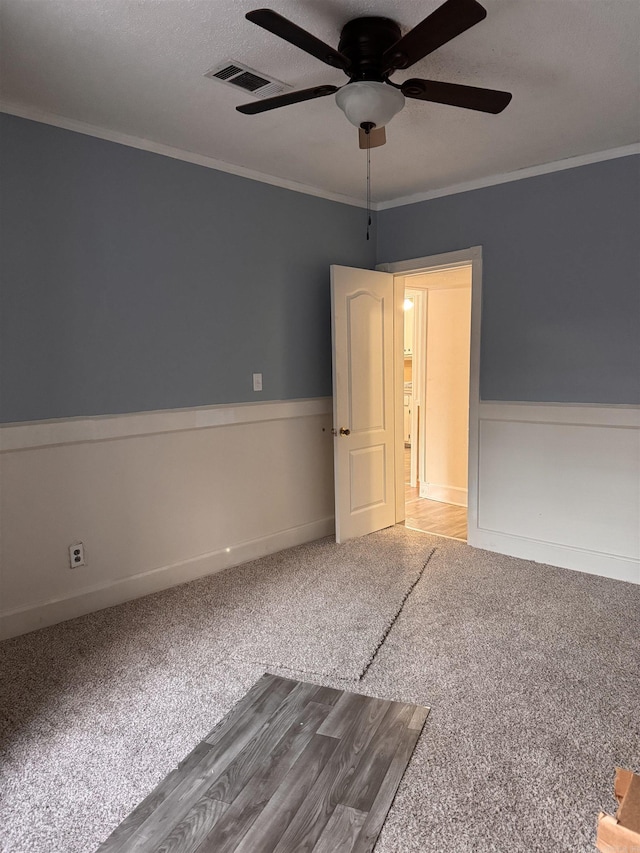 unfurnished room featuring ceiling fan, crown molding, carpet, and a textured ceiling