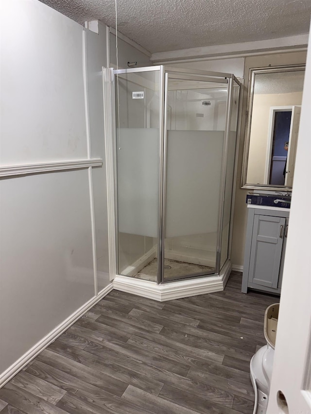 bathroom featuring vanity, hardwood / wood-style floors, a textured ceiling, and a shower with shower door