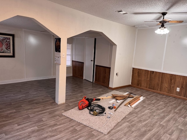 bonus room featuring wood-type flooring, a textured ceiling, ceiling fan, and wood walls