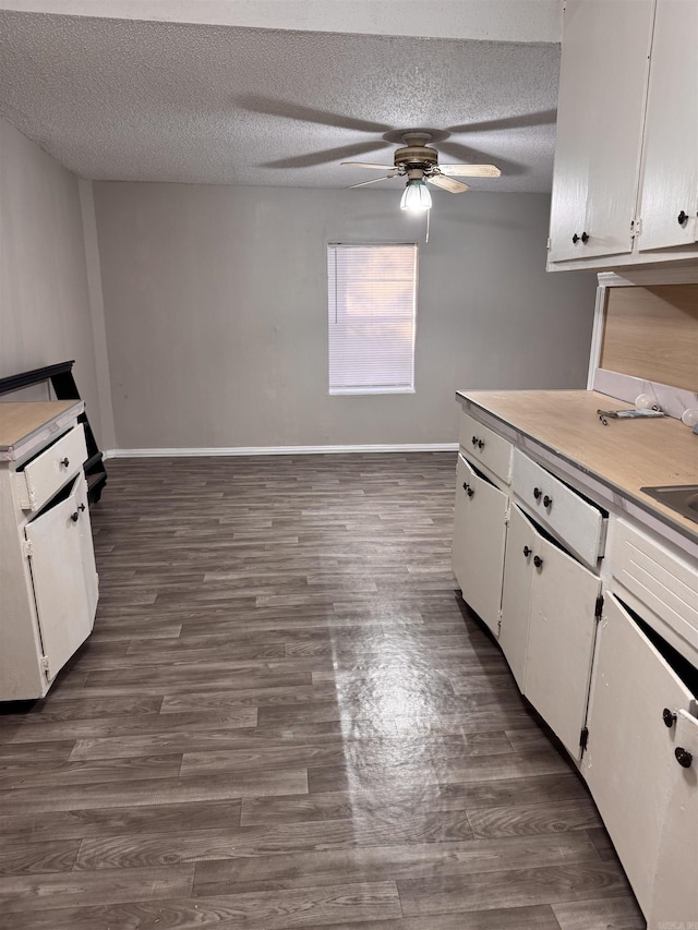 kitchen with white cabinets, a textured ceiling, and dark hardwood / wood-style floors