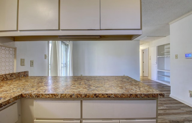 kitchen with built in shelves, hardwood / wood-style floors, and a textured ceiling