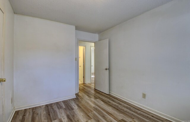 unfurnished room with a textured ceiling and light wood-type flooring