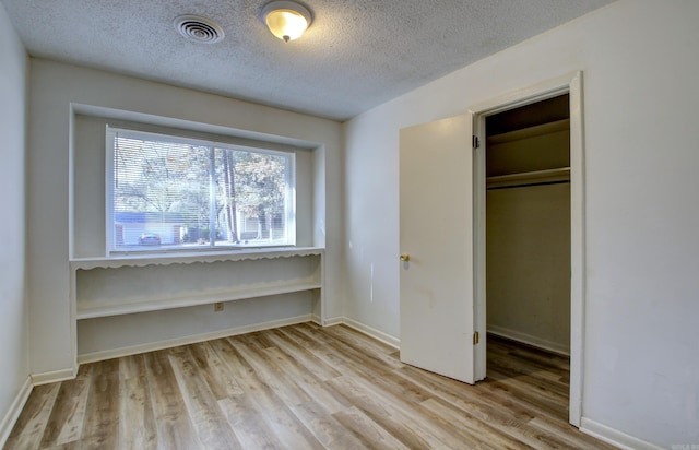 unfurnished bedroom featuring a closet, a textured ceiling, and light wood-type flooring