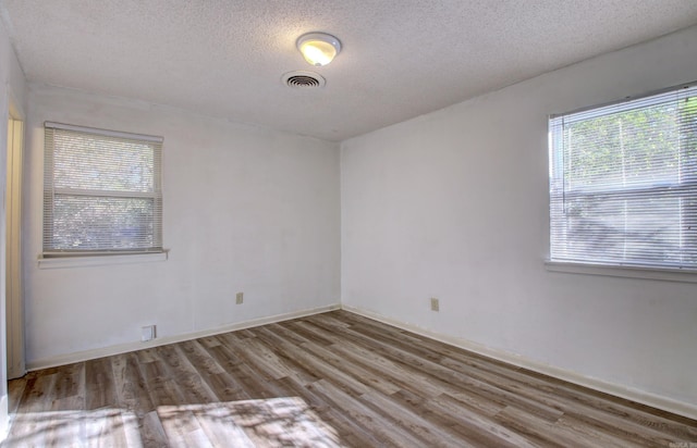 unfurnished room featuring wood-type flooring and a textured ceiling