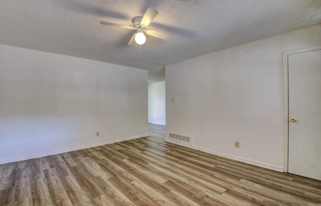 spare room with a textured ceiling, light wood-type flooring, and ceiling fan