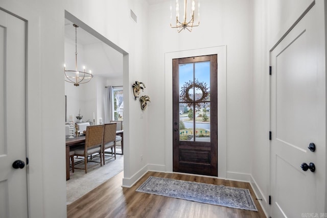 foyer entrance featuring hardwood / wood-style floors, a towering ceiling, and a chandelier