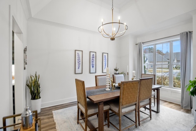 dining area with hardwood / wood-style flooring, ornamental molding, and an inviting chandelier