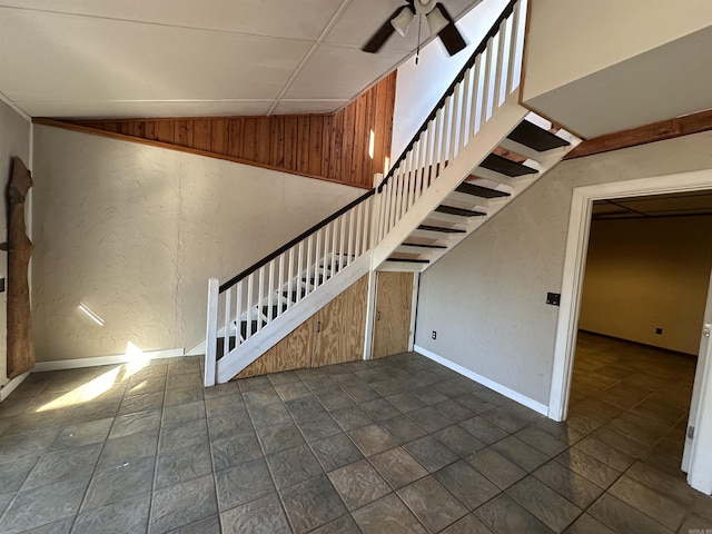 stairs featuring ceiling fan, lofted ceiling, and wooden walls