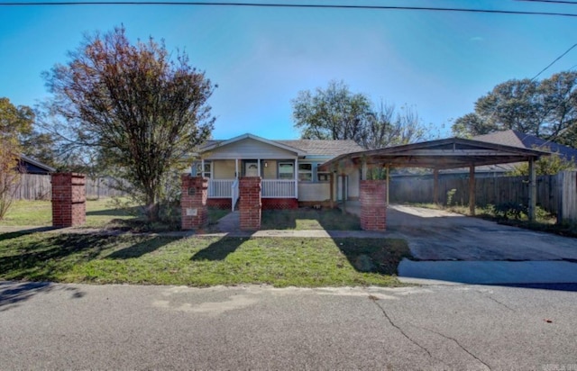 ranch-style home featuring covered porch, a front yard, and a carport