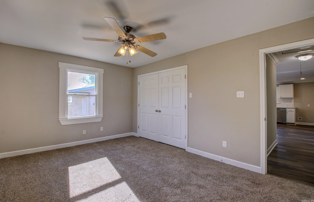 unfurnished bedroom with ceiling fan, dark carpet, and a closet