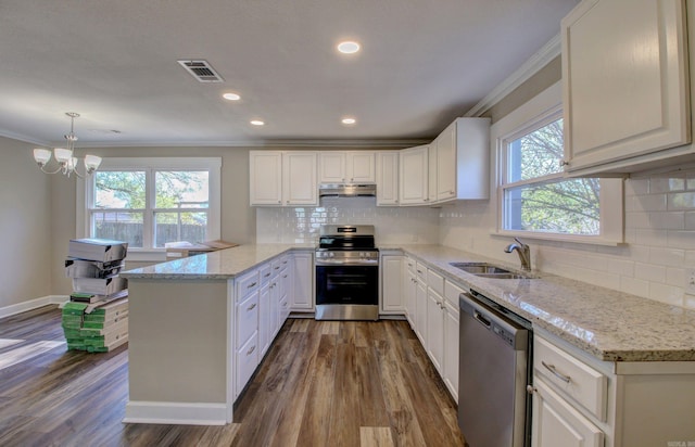 kitchen featuring white cabinets, hanging light fixtures, appliances with stainless steel finishes, dark hardwood / wood-style flooring, and kitchen peninsula