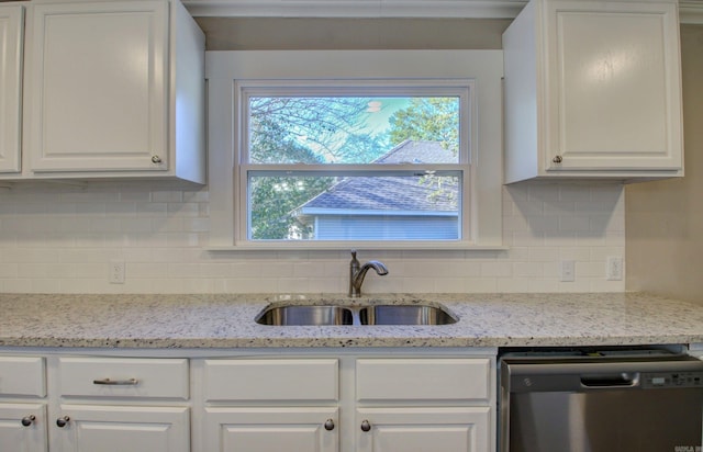 kitchen with decorative backsplash, light stone counters, stainless steel dishwasher, sink, and white cabinetry