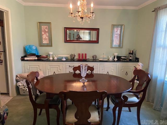 dining room with light colored carpet, a chandelier, and ornamental molding