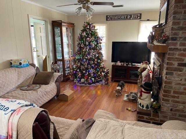 living room featuring hardwood / wood-style floors, ceiling fan, and ornamental molding